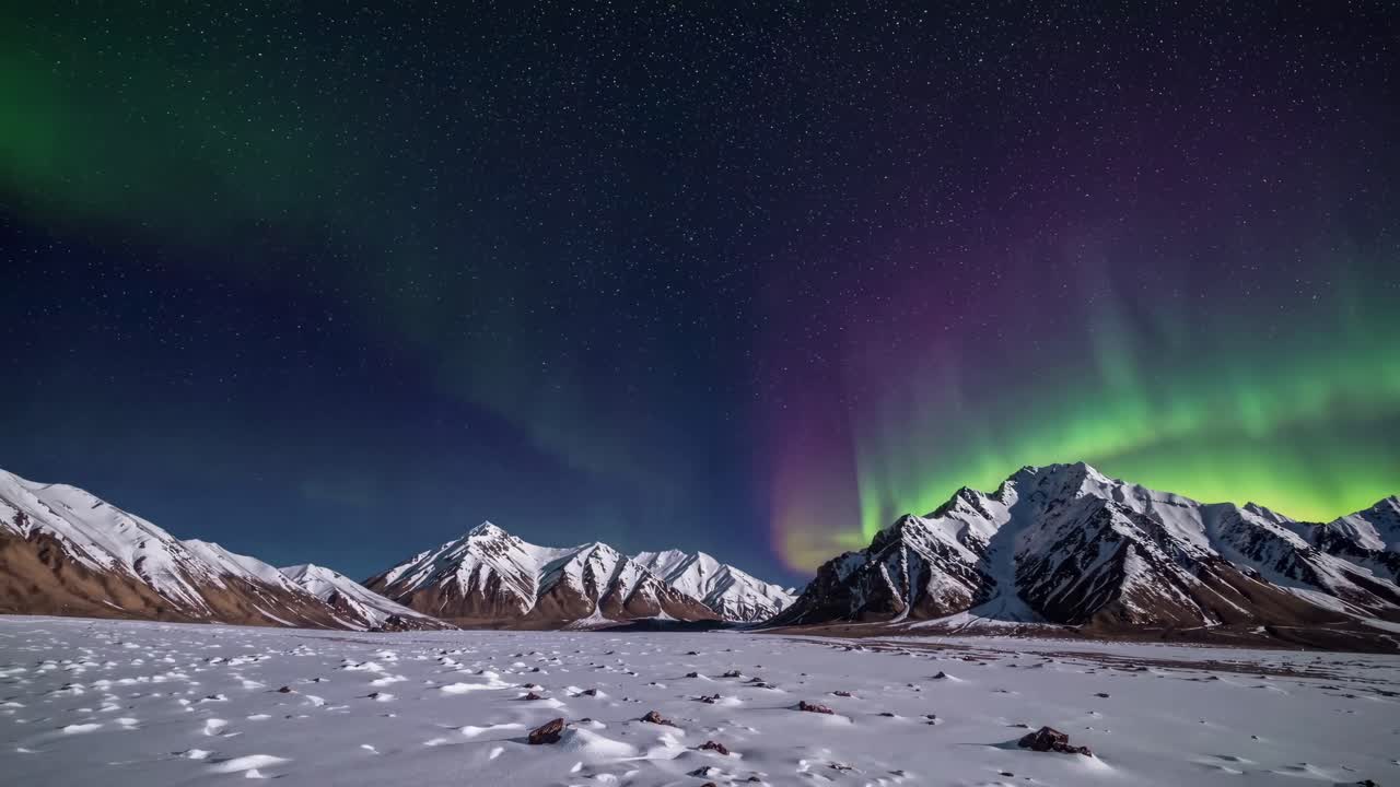 Wide-angle shot of snow-covered mountains under vibrant northern lights, resembling a time-lapse