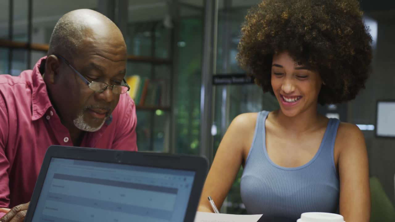 Diverse male and female business colleagues talking and using laptop