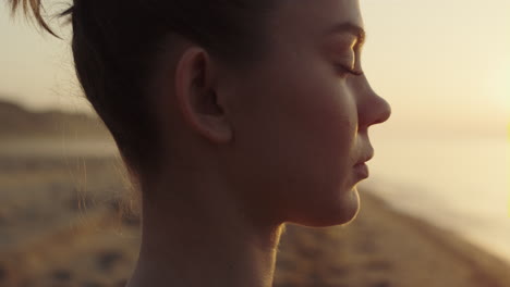 portrait yogi woman meditating on seacoast. girl making breathing exercises.