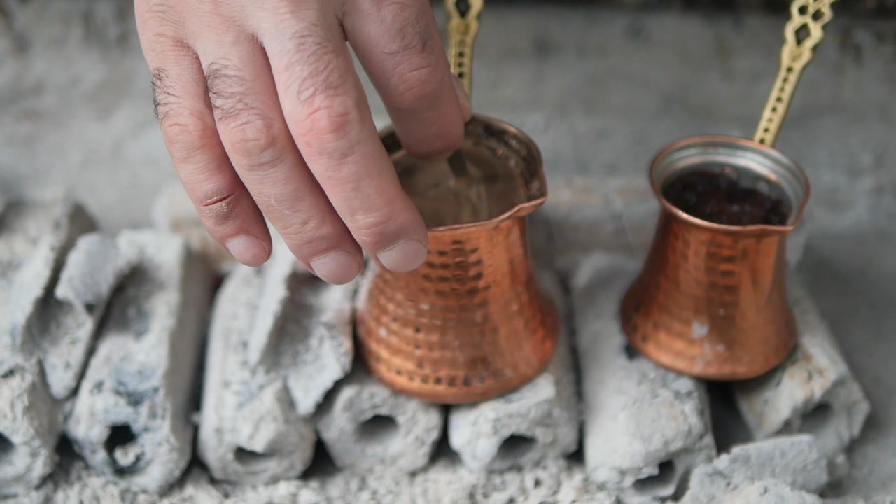 Hand Stirring Traditional Turkish Coffee in Copper Pot on Hot Charcoal