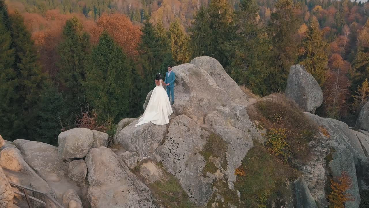 los recién casados están en una ladera alta de la montaña. el novio y la novia.