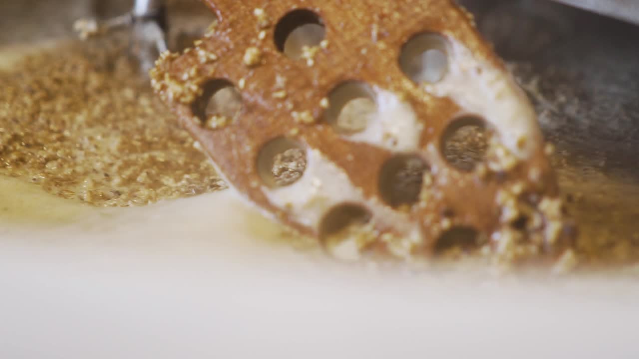 수제 맥주 양조 - 구멍이 있는 나무 숟가락을 사용하여 양조 탱크에서 맥아 곡물을 물과 혼합 - 극도로 가까운 슬로모