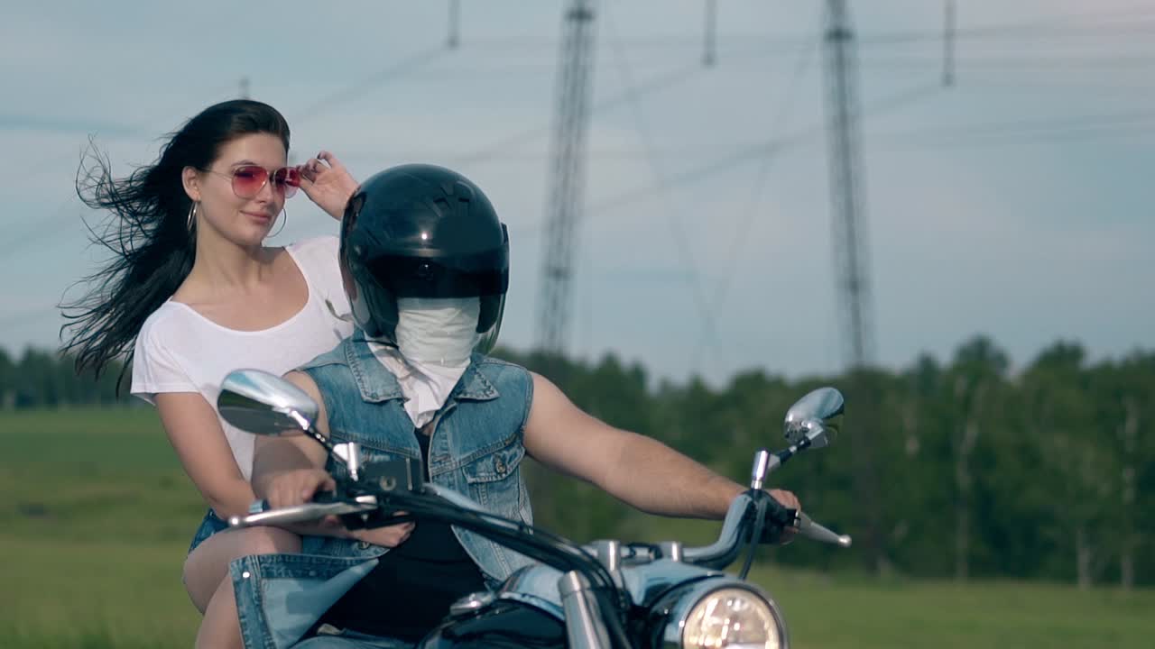 예쁜 여자가 뒷좌석에서 오토바이를 타고 선글라스를 수리합니다.