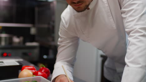 chef writing list of food ingredients in restaurant kitchen