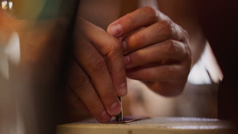 craftsman makes hole in leather belt with tool at table