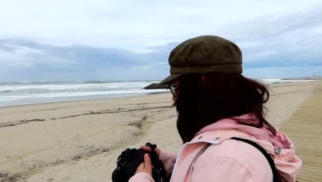 mujer fotógrafa en la playa cubriendo la lente de la cámara