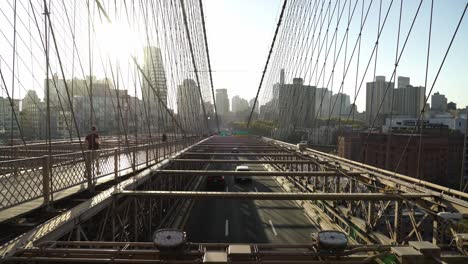 commuters crossing brooklyn bridge in new york on a sunny evening