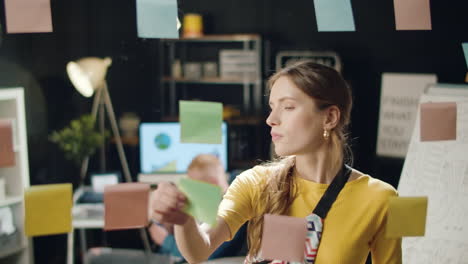 closeup hipster woman sticking notes on transparent wall in business office