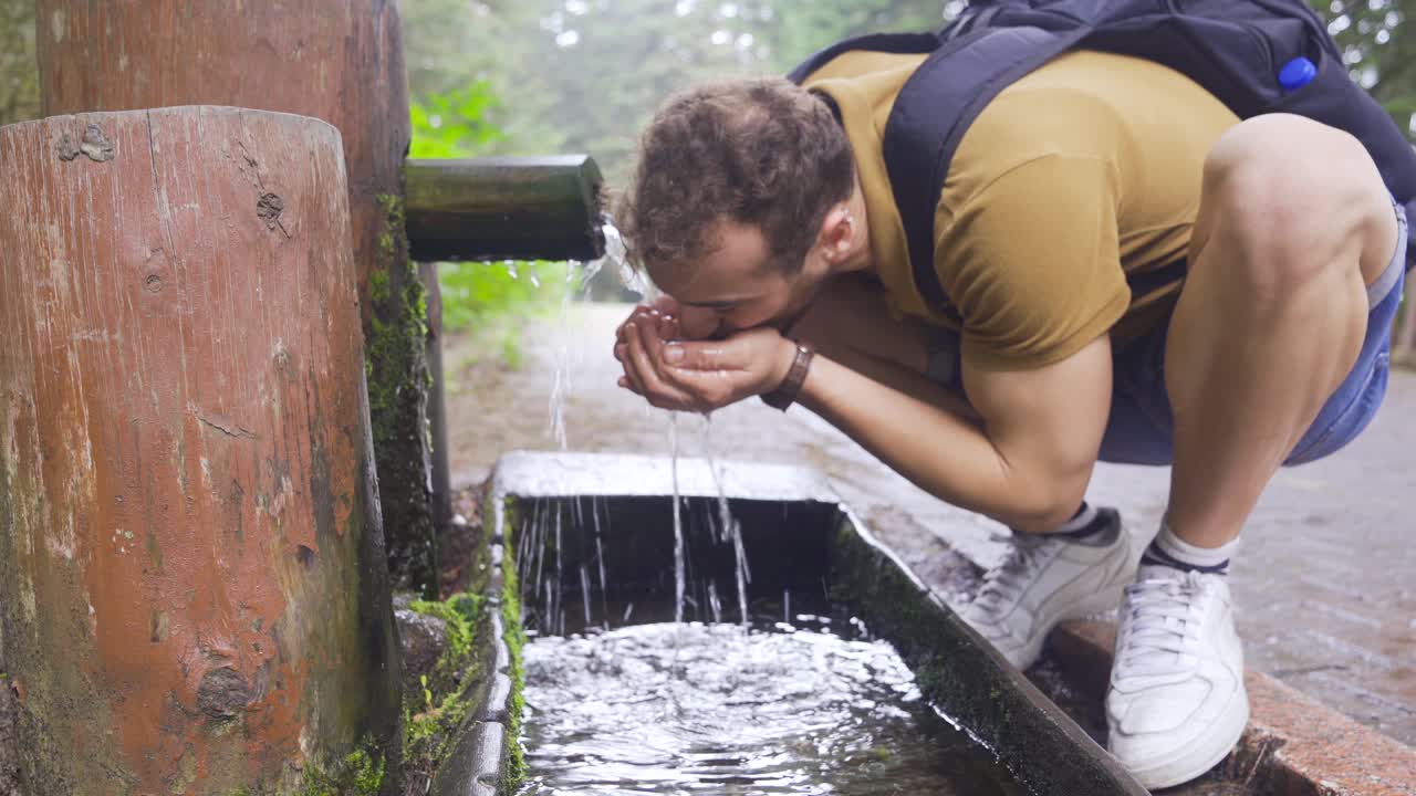 hombre bebiendo agua de un manantial de montaña.