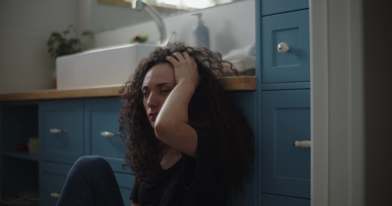 Upset woman sitting on a bathroom floor