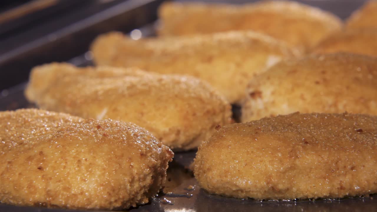 Golden breaded chicken fillets baking in the oven, timelapse