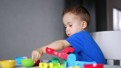 cute caucasian baby playing peacefully at home. lovely baby boy dealing with plasticine and bright toys on his desk.