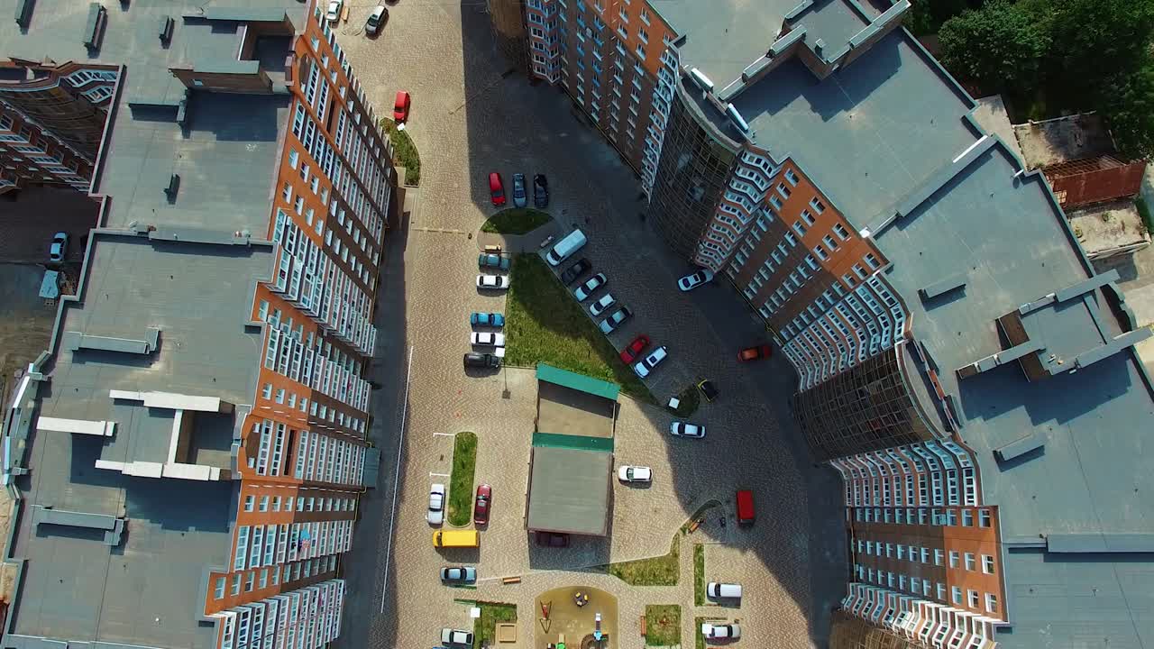 View from above on a modern residential complex. Beautiful design of a car parking and playground near the apartment buildings. Aerial view.