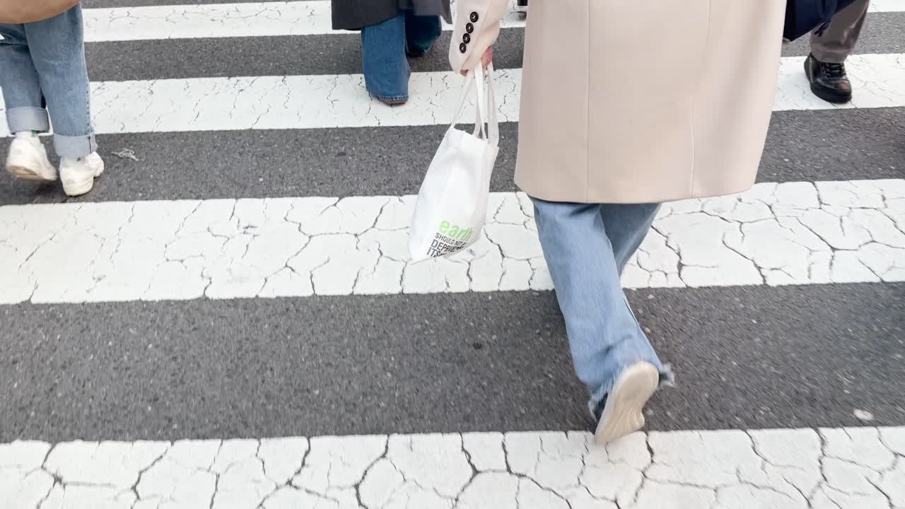東京のゼブラ柄横断歩道を渡る歩行者を、ローアングルから撮影した映像。