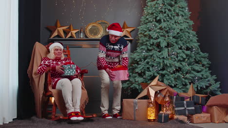 senior family couple grandmother grandmother presenting christmas gift boxes to each other at home