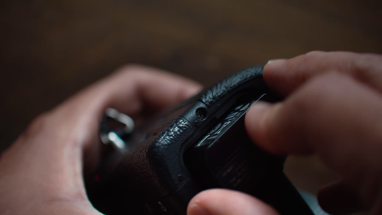 Person Inserts Rechargeable Battery Into DSLR Camera