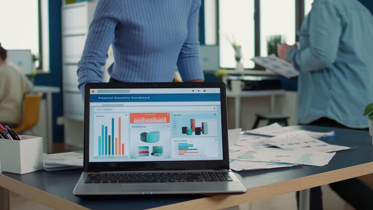 Closeup of laptop screen showing moving charts and financial statistics on desk
