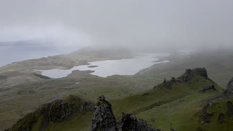 imágenes aéreas de drones de 4k que vuelan cerca de rocas oscuras en el viejo hombre de storr en la isla de skye cerca de portree escocia niebla niebla y lago en segundo plano