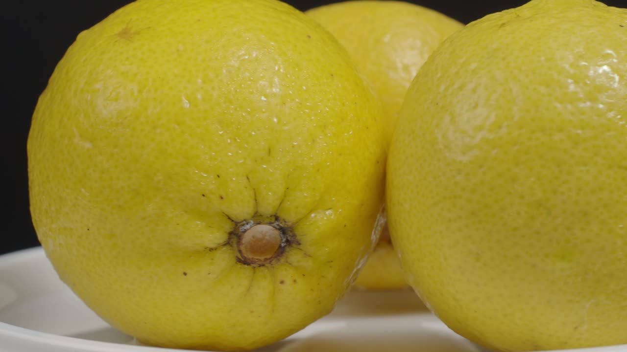 limón delicioso moviéndose en la mesa giratoria. limones sabrosos aislados en el fondo negro. limones amarillos enteros y medio están aislados en fondo oscuro. cerca. representan agrio y refrescante menú de bebidas.