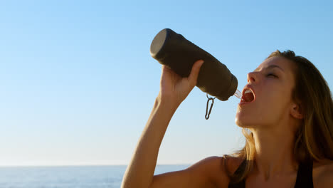 fit woman drinking water in the beach 4k