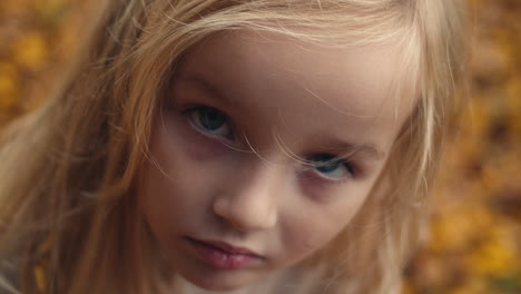 young girl with blond hair and blue eyes stares intensely into camera