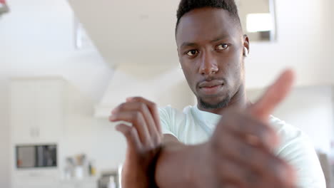 Focused-african-american-man-stretching-in-sunny-living-room,-slow-motion