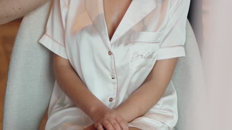 bride in a soft satin robe, sitting calmly before getting ready for the wedding ceremony