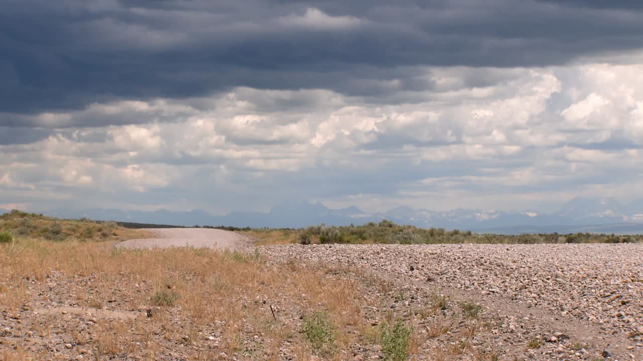 un largo camino de tierra que se dirige hacia los grand tetons desde el lado de idaho