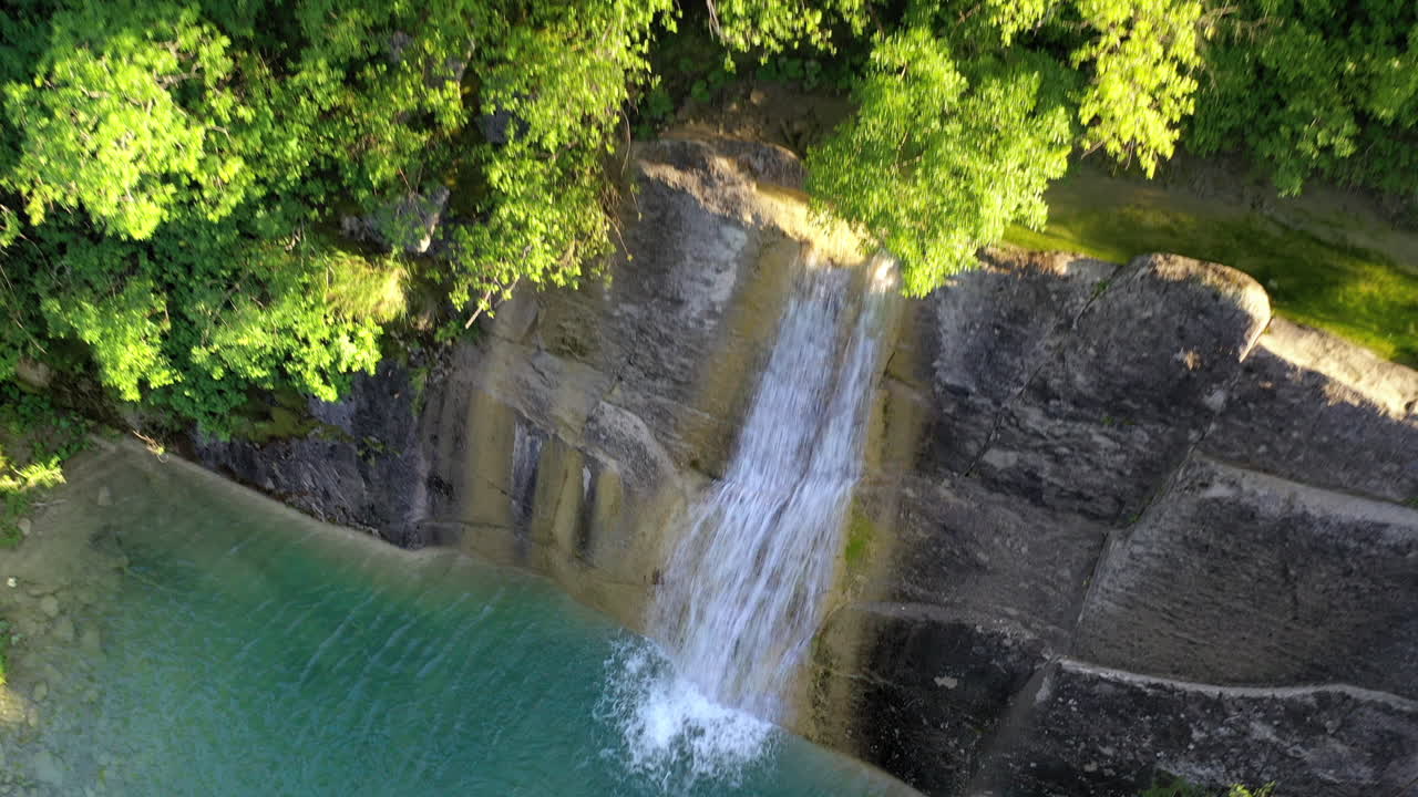 Inquadratura con drone medio-ampia in dolly out delle cascate Slap Veli Vir e della vegetazione circostante durante il giorno.