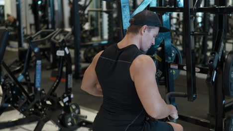 fit muscular man training back lat muscles in seated row machine at gym