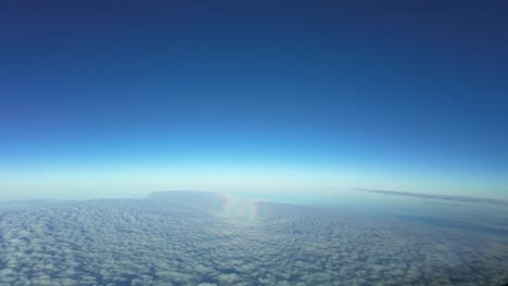 aerial pov of the halo of a jet airplane while flying over a layer os stratus clouds with the sun at the back