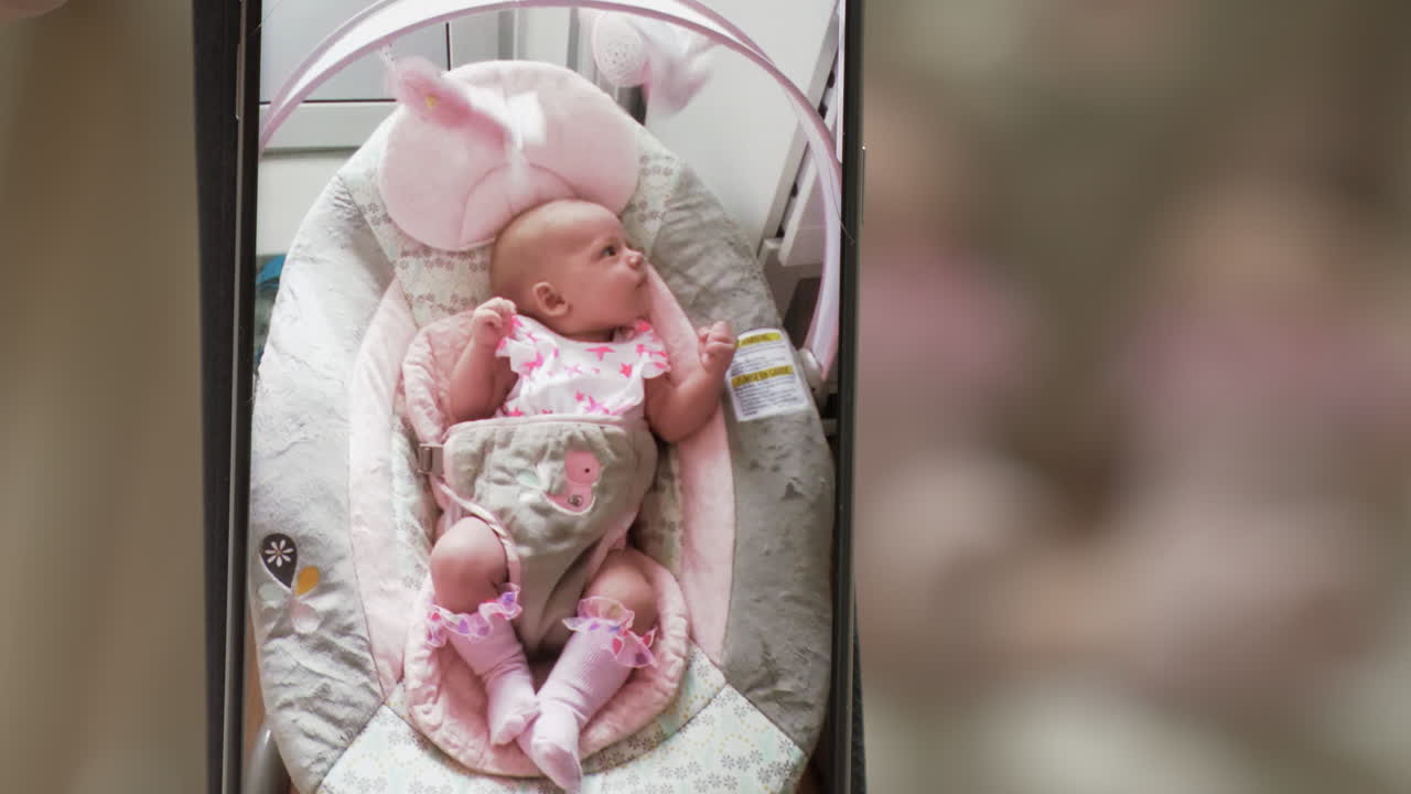 Neonata su una sedia a dondolo, la mamma fa un video con il cellulare