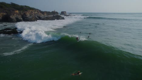 vista aérea de seguimiento de surfista montando olas a lo largo de punta zicatela oaxaca soleada costa azul del mar, méxico