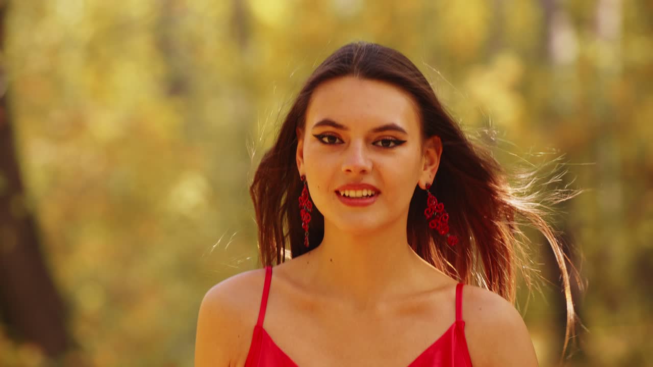 Un viaggio affascinante nella natura: una giovane donna in un abito rosso incantevole ammira i colori autunnali sullo sfondo di una foresta serena