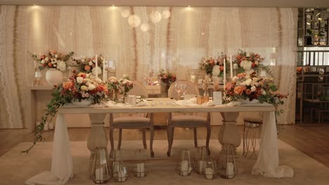 romantic wedding sweetheart table with flowers and candles indoors