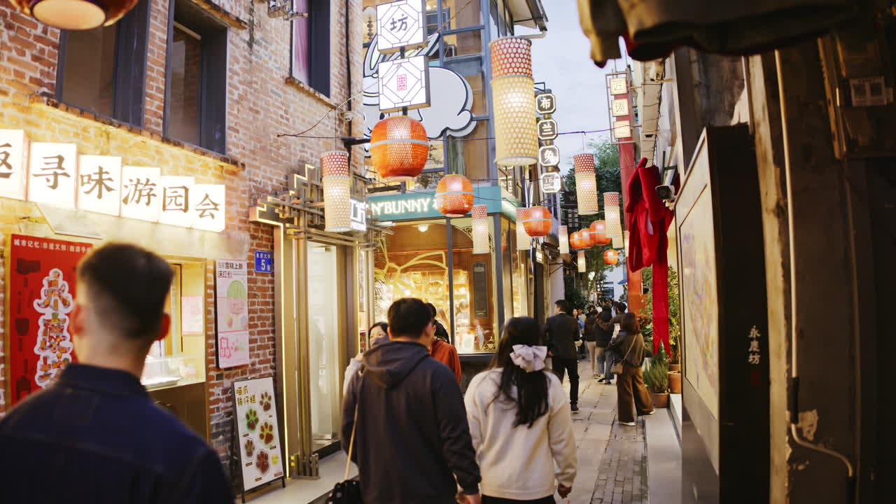 Persone che camminano in una vivace strada tradizionale asiatica con lanterne al crepuscolo.