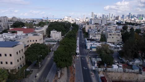 new city train driving through suburban area towards city center of tel aviv, aerial view