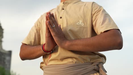 meditando con las manos en posición de hatha yoga al amanecer en la cima de la colina por una persona india irreconocible en cámara lenta