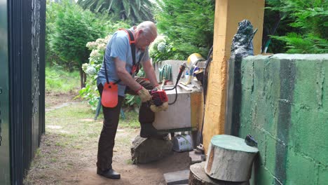 senior man pulling rope starting petrol driven trimmer for garden