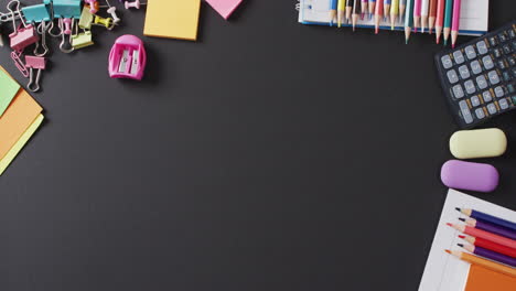 video of school supplies and notebooks, paper clips, pens over black background