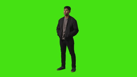 Full-Length-Shot-Of-Fed-Up-Casually-Dressed-Young-Man-Standing-Against-Green-Screen-Putting-Hands-In-Pockets