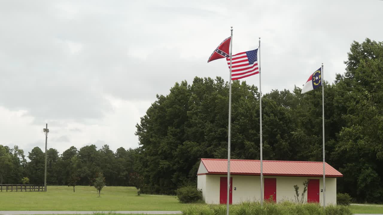 US, confederate civil war, and the North Carolina State flags waving in the wind over an historic Civil War battle field