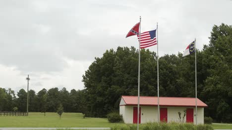 us, confederate civil war, and the north carolina state flags waving in the wind over an historic civil war battle field