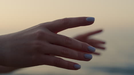 woman hands reaching forward near ocean close up. girl practicing yoga asana.