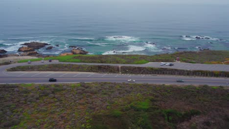 slide follow aerial drone shot of cars driving in fog on pacific coast highway crossing bridge by san gregorio beach in california, usa