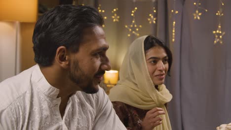 muslim family sitting around table at home eating meal to celebrate eid 2