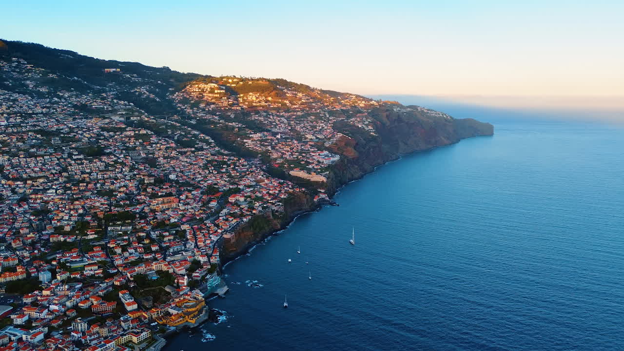 Densely built rocky landscape of the Madeira Islands, Portugal. Aerial view on the waterscape of the Atlantic Ocean near the mountainous shore.