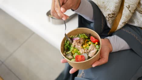 una mujer comiendo una ensalada de atún.