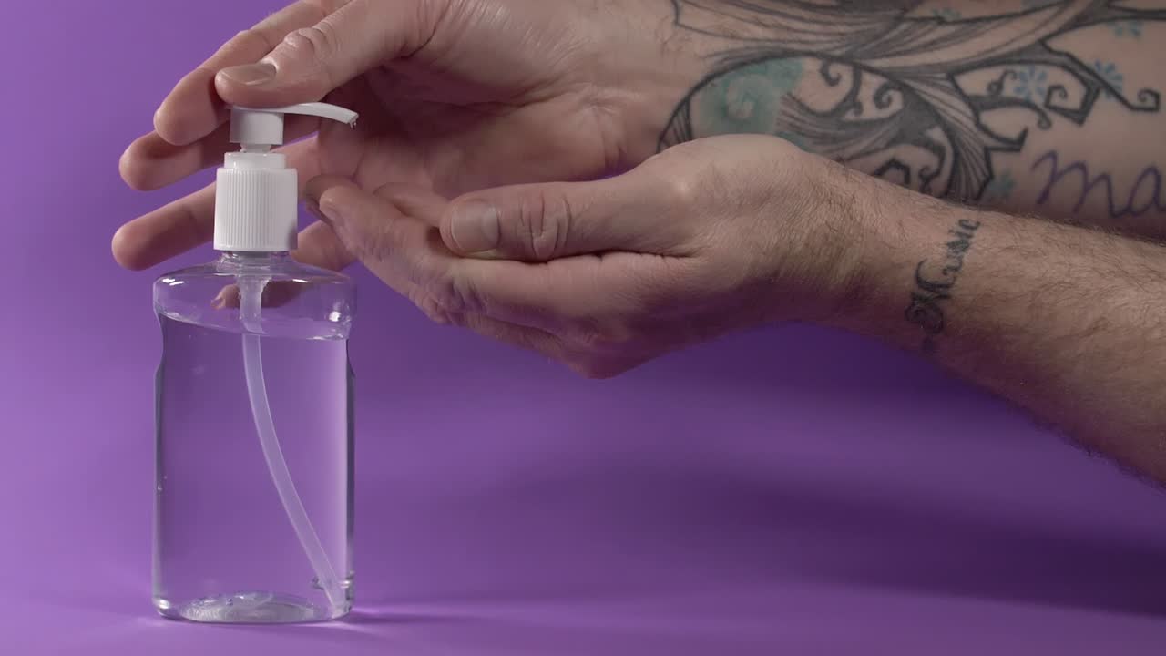 esterilización manual con gel desinfectante a base de alcohol sobre fondo morado