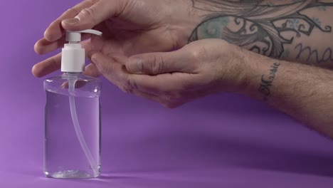 hand sterilization using alcoholic based sanitizer gel on purple background